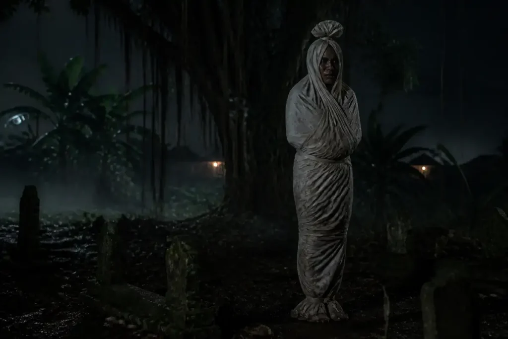 Sosok pocong realistis berdiri di pemakaman desa Indonesia pada malam berkabut